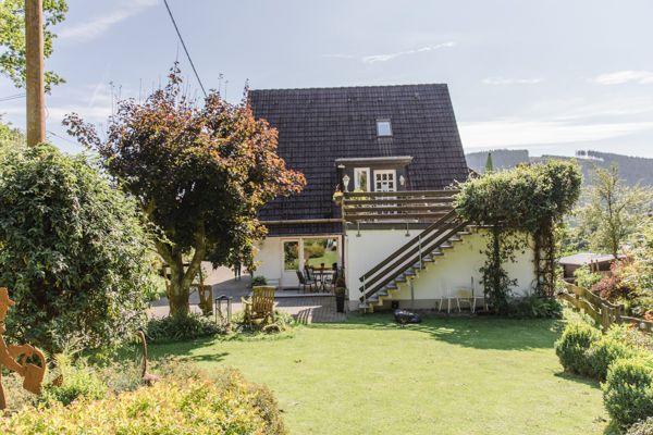 Haus mit Garten, Terrasse und Holzstufen zur Veranda.