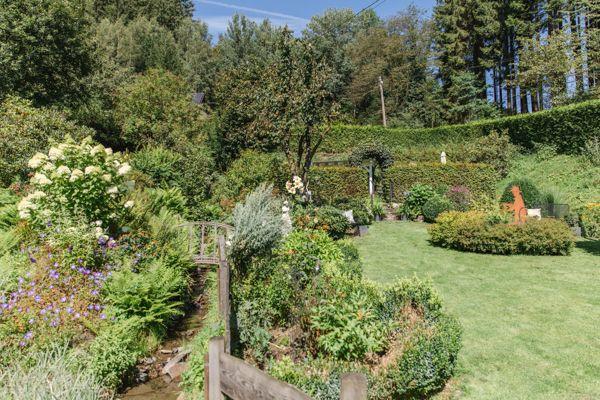 Garten mit Grasfläche, Sträuchern und einem kleinen Teich.