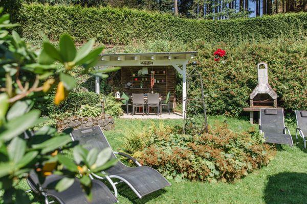 Garten mit Pavillon, Liegestühlen und Grillplatz.