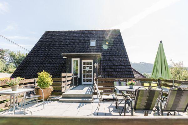 Haus mit Terrasse, Tisch, Stühlen und grünem Sonnenschirm