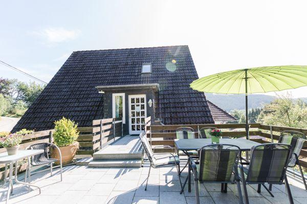 Haus mit Terrasse, Tisch, Stühlen und grünem Sonnenschirm