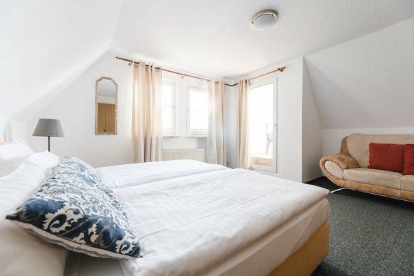 Schlafzimmer mit Doppelbett, Sofa und Fenstern