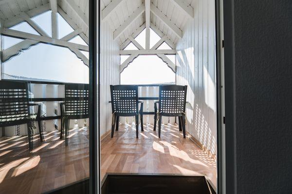 Terrasse mit Tisch und Stühlen unter Dachkonstruktion mit Holzboden