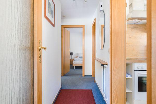 Flur mit Schlafzimmer und Küche. Holztüren und roter Teppich.