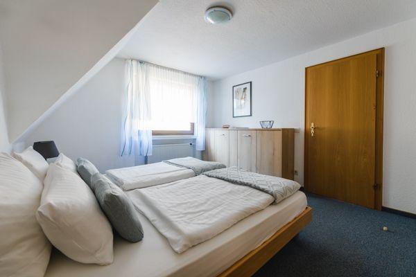 Schlafzimmer mit Doppelbett, Fenster und Holzschrank