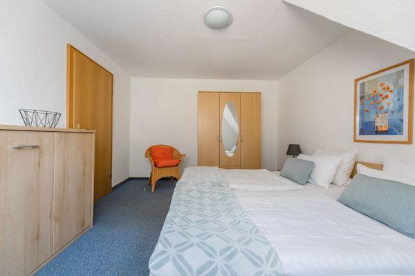 Schlafzimmer mit Bett, Kleiderschrank und Stuhl