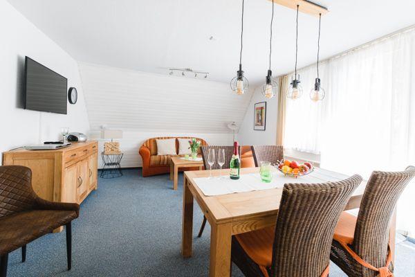 Wohn- und Essbereich mit Tisch, Stühlen, Sofa und TV.