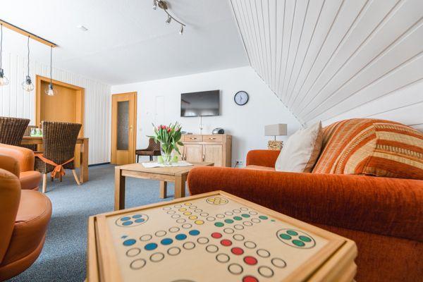 Wohnzimmer mit Sofa, Tisch und Fernseher unter schrägem Dach