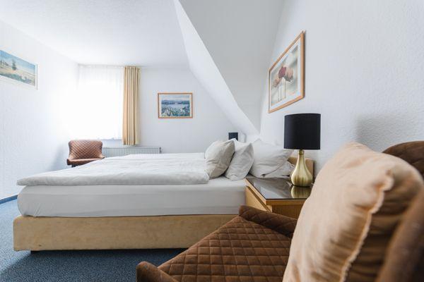 Schlafzimmer mit Bett, Nachttisch und Fenster unter Dachschräge