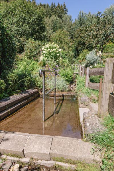 Außenliegender Whirlpool mit Metallgeländer und umgebendem Garten.