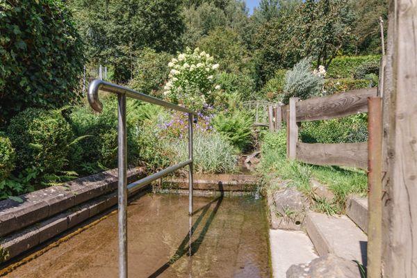 Ein kleiner Bach mit Metallgeländer und Holzgeländer im Garten.