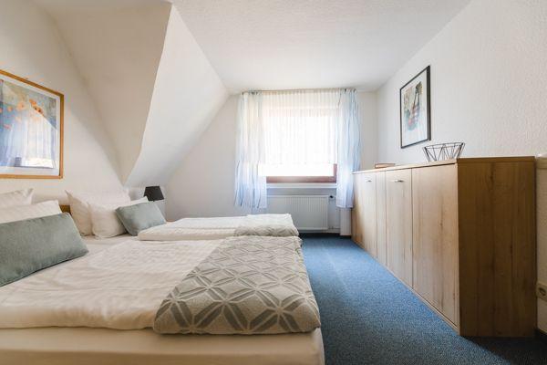 Zimmer mit Doppelbett, Fenster und Holzschrank