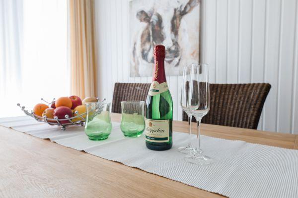 Esstisch mit Flasche, Gläsern und Obstschale