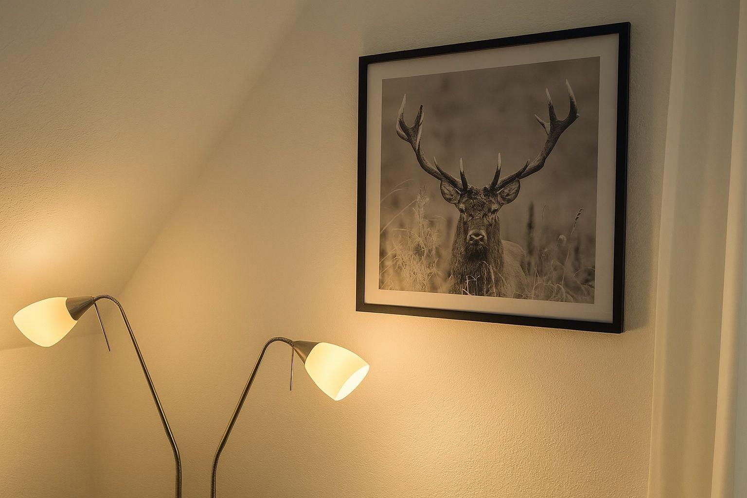 Two floor lamps and a framed picture of a deer on the wall.