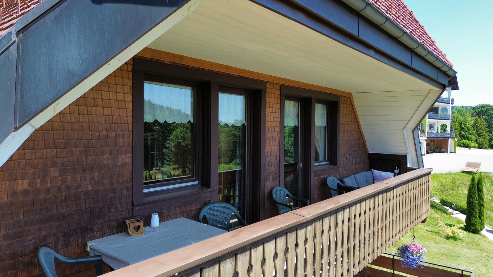 Terrace with table, chairs, and view of forest.