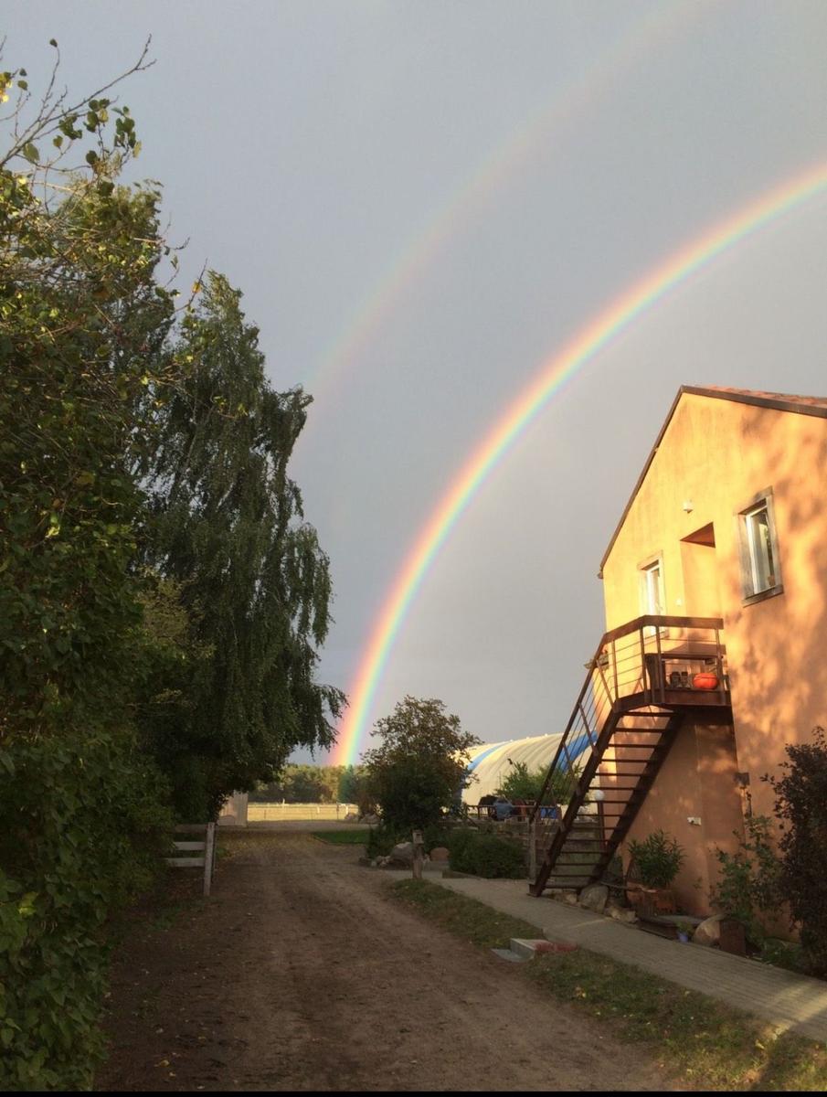 Ein Haus mit Balkon und Treppe unter einem Regenbogen.