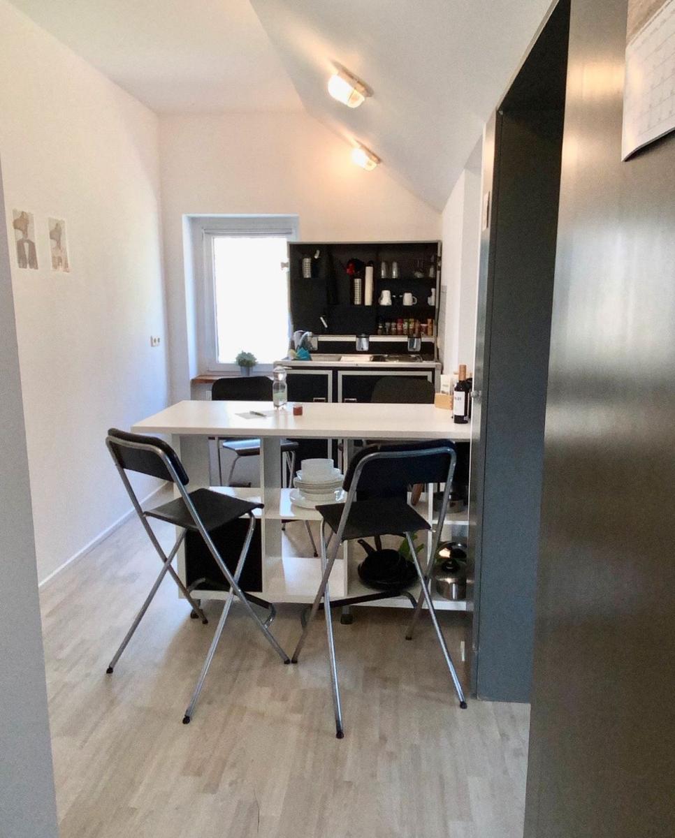 Küche mit Esstisch und Stühlen, Fenster und Schränke sichtbar.