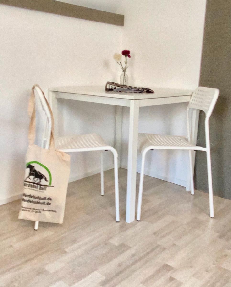 Weißer Tisch mit zwei Stühlen und Blumen in Vase