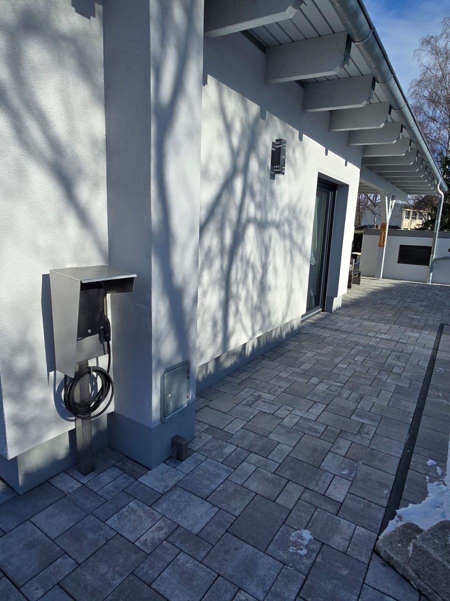 Außenbereich mit Ladesäule und gepflastertem Weg an modernem Haus