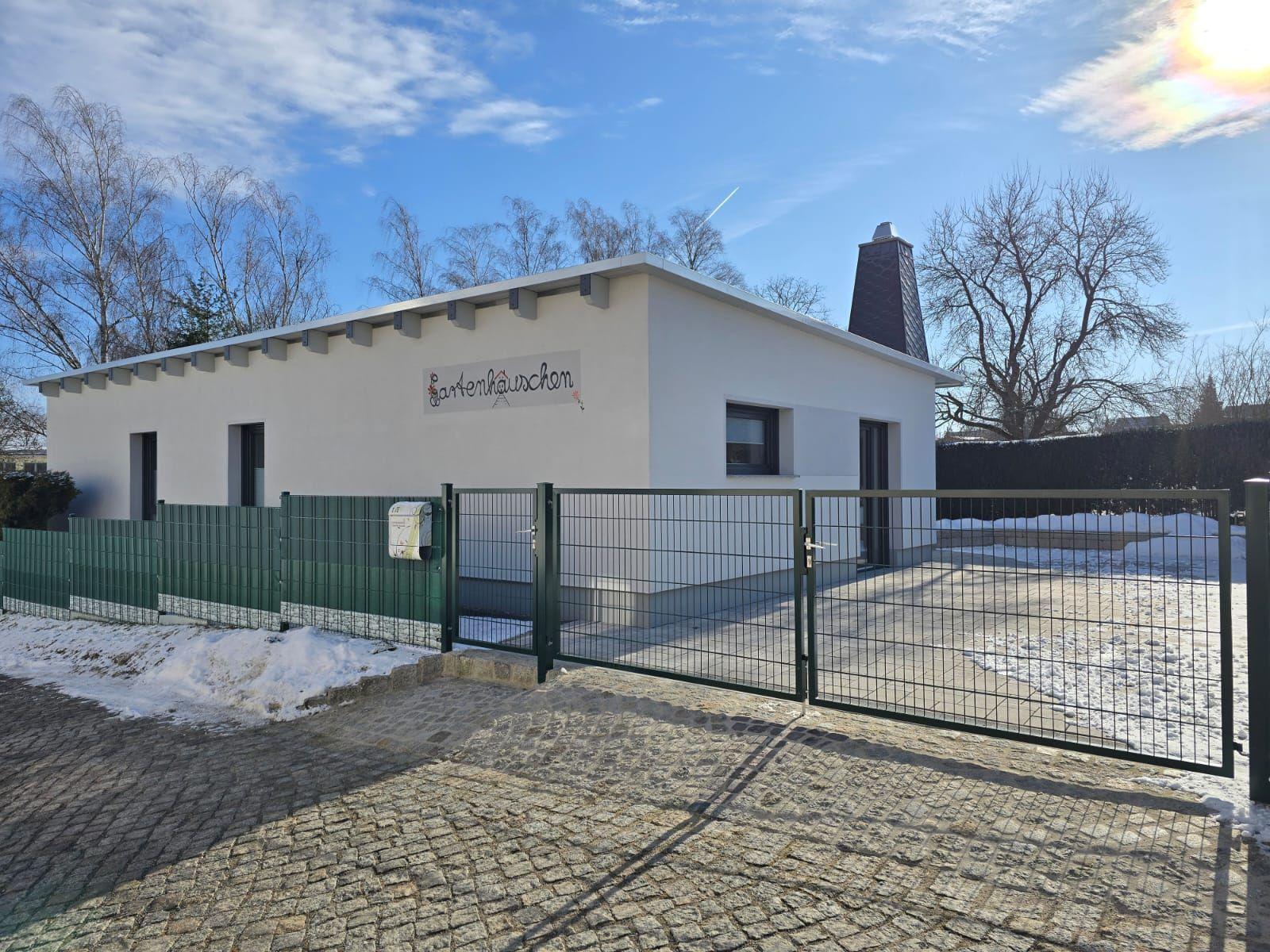 Modernes Gartenhaus mit Gittertor und Schneeflächen.