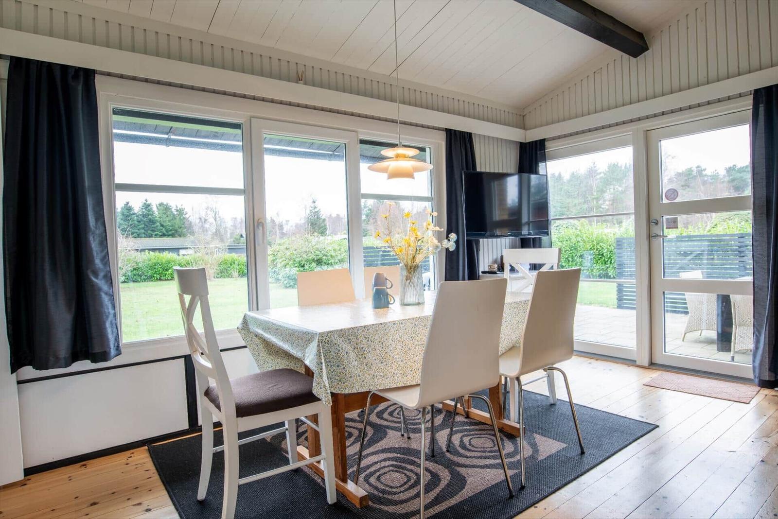 Dining room with table, chairs, and windows to the outdoor terrace.