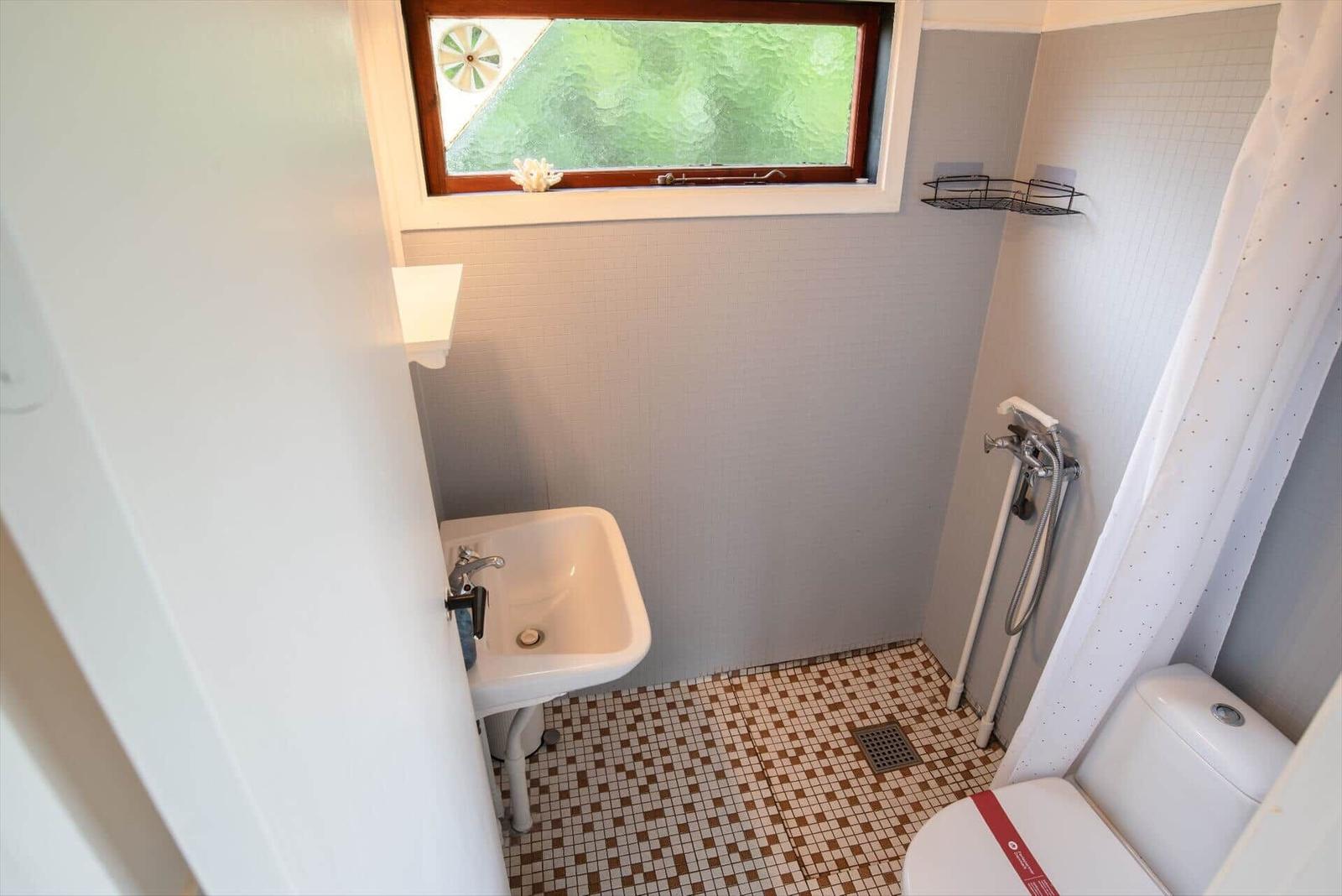Bathroom with sink, toilet, and shower under window
