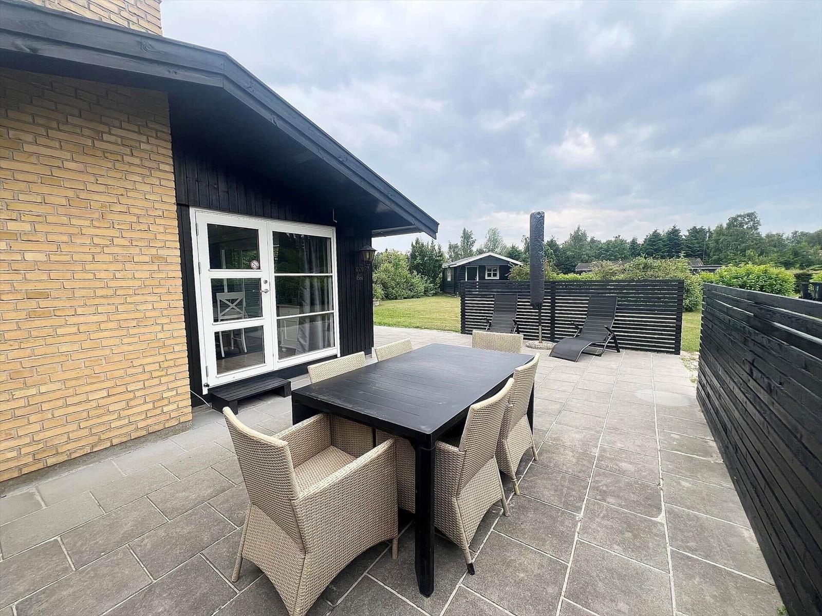 Terrace with table, chairs, loungers, and garden area.