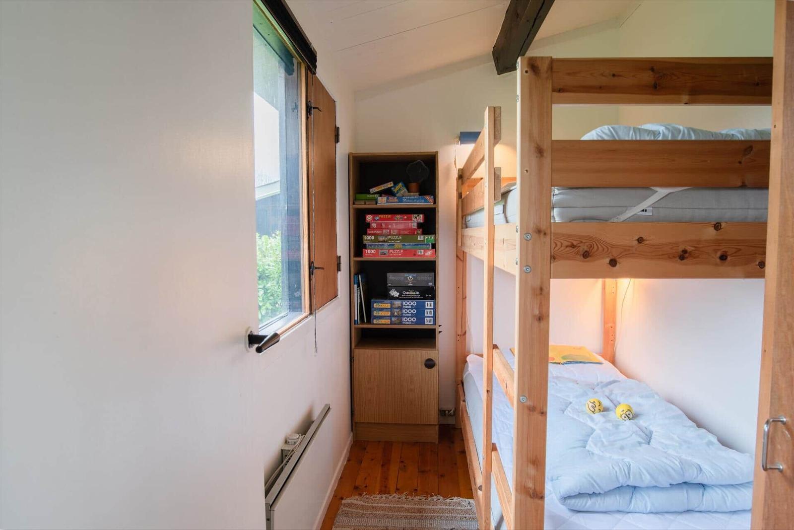 Room with wooden bed, bookshelf, and window.