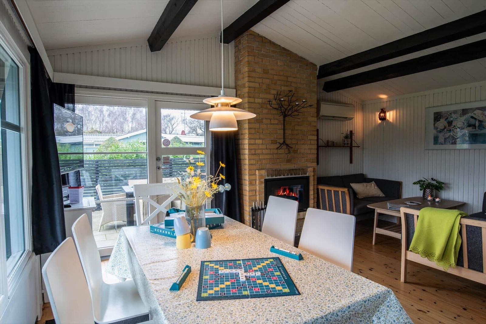 Dining area with table, chairs, and fireplace. Living area with sofa and window.
