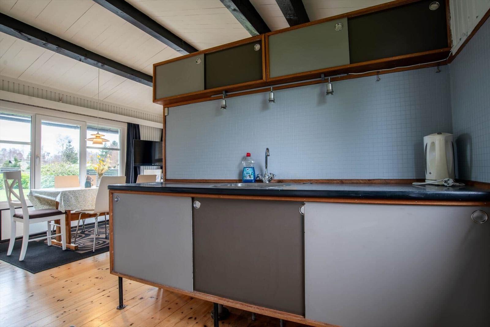 Kitchen with countertop, sink, and kettle. Dining area with table and chairs.