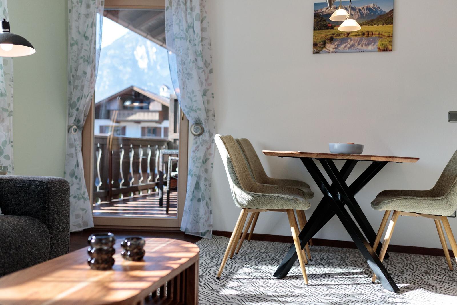 Essbereich mit Tisch und Stühlen. Blick auf Balkon und Berge.