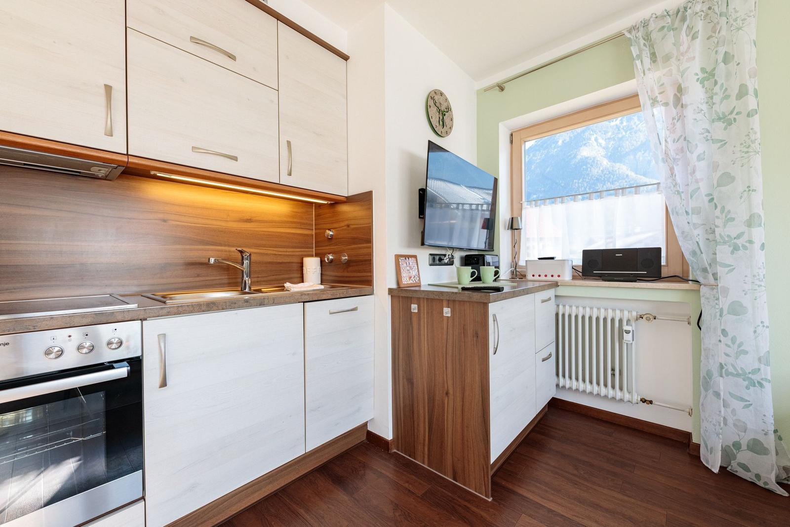 Küche mit Holzoptik, Fenster mit Bergblick und TV-Wand