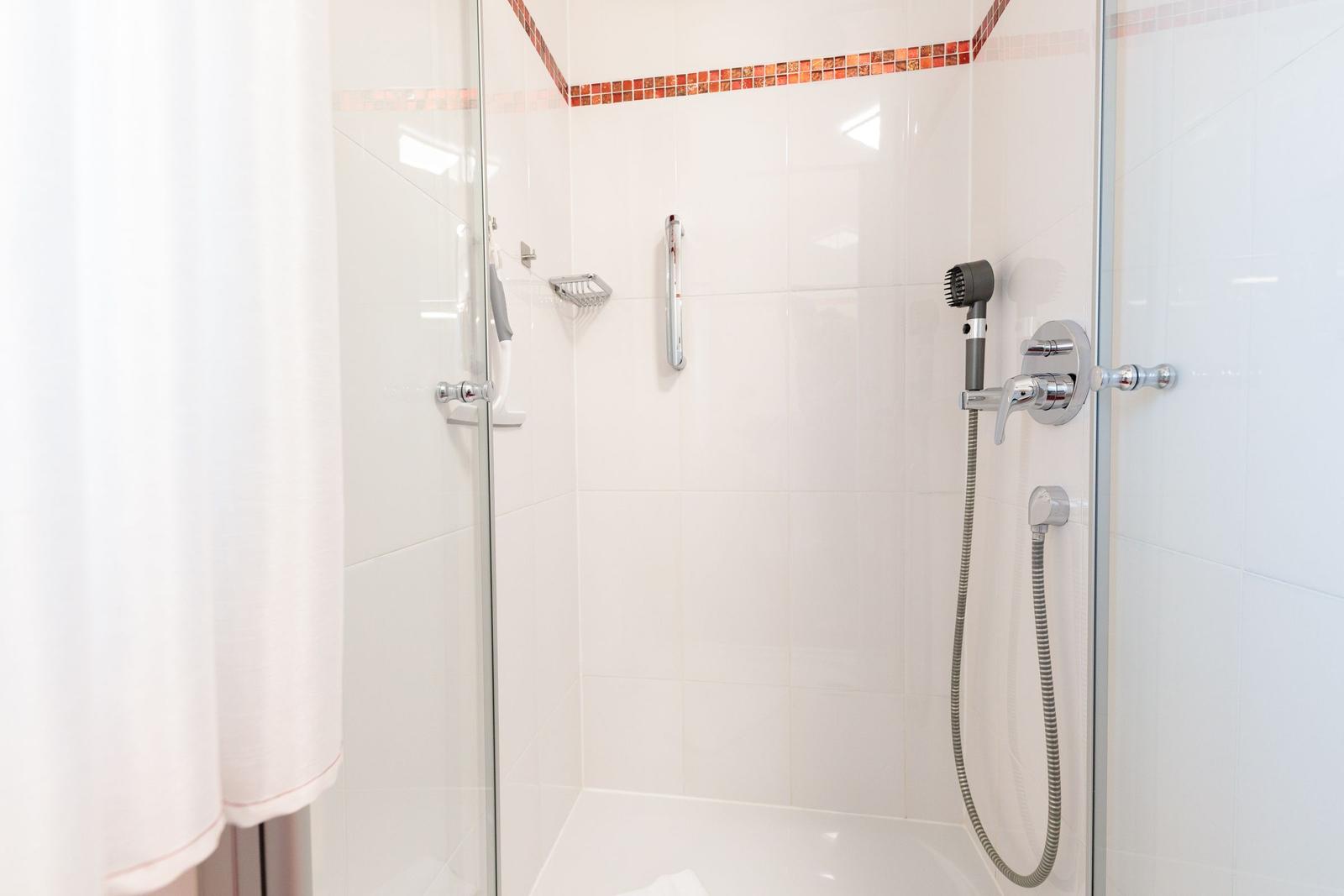 Dusche mit Glaswand, Handbrause und Handtuchhalter