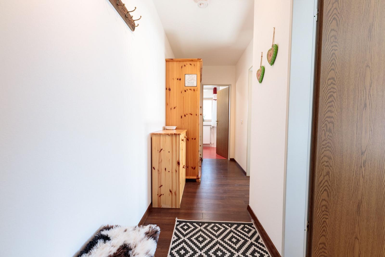 Flur mit Holzmöbeln, Teppich und Wanddekoration.