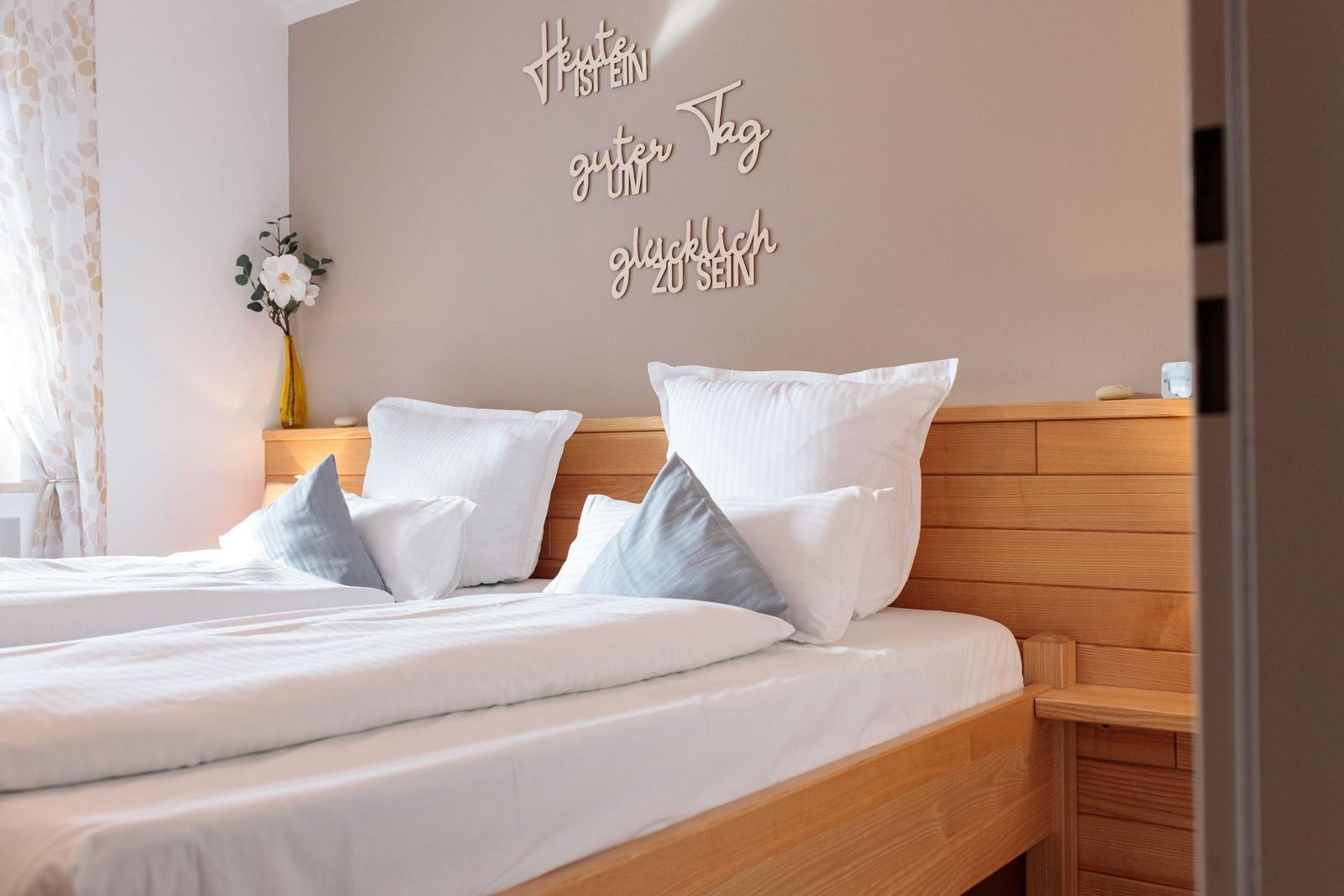 Schlafzimmer mit Holzbett, weißen Kissen und Wanddekoration.