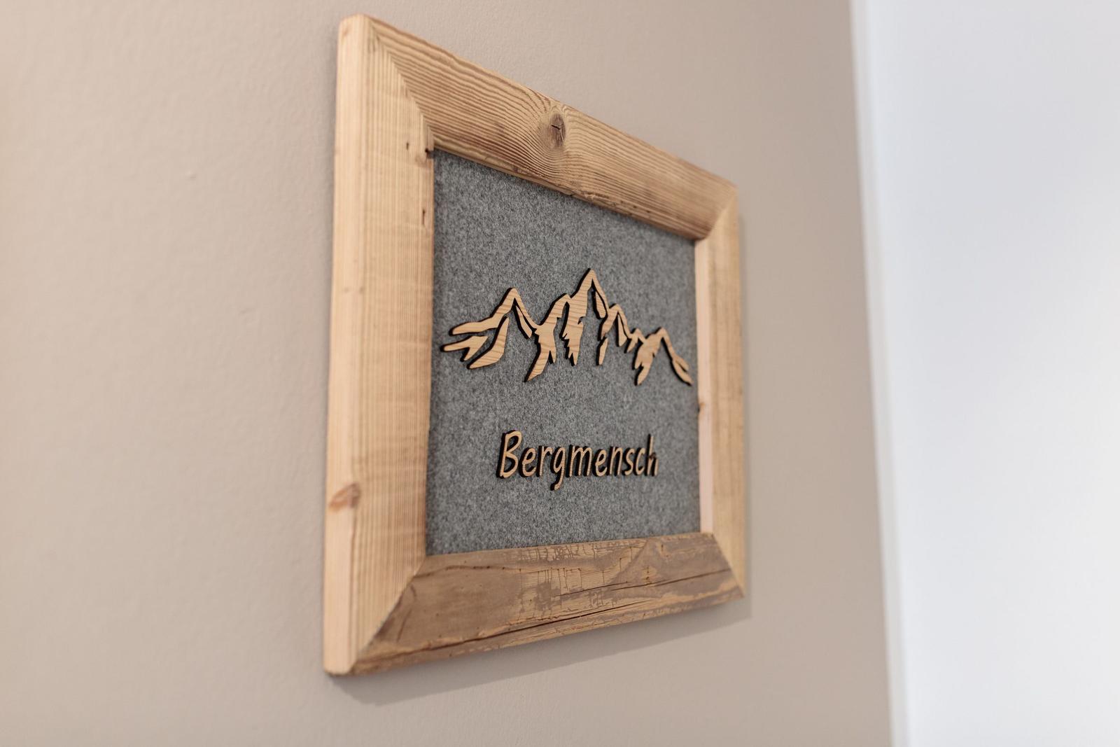 Holzrahmen mit Bergmotiv und Schrift Bergmensch an Wand
