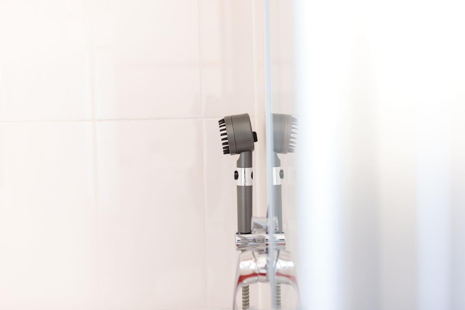 Duschbrause mit Duschvorhang und weißen Fliesen