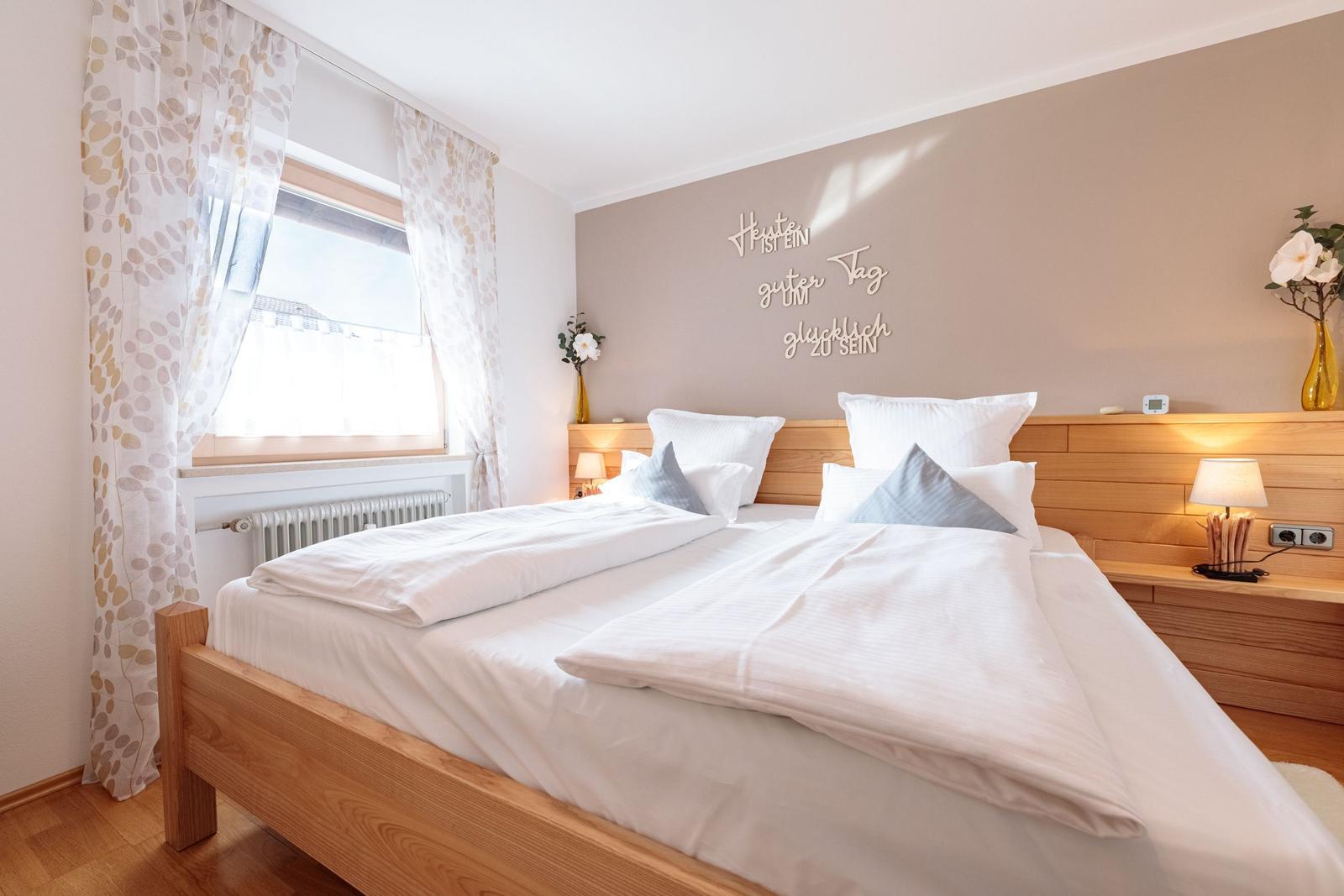 Ein Schlafzimmer mit Holzbett, Fenster und Wanddekoration.