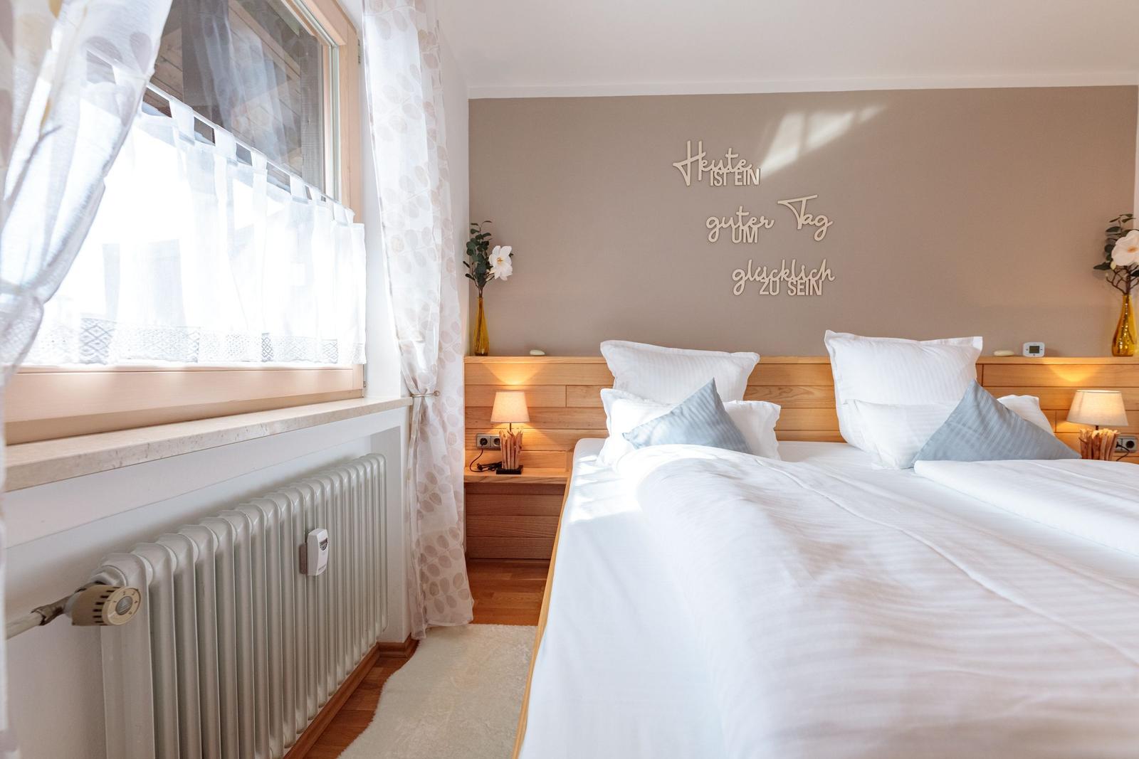 Schlafzimmer mit Doppelbett, Holz-Kopfteil und Wanddekoration.