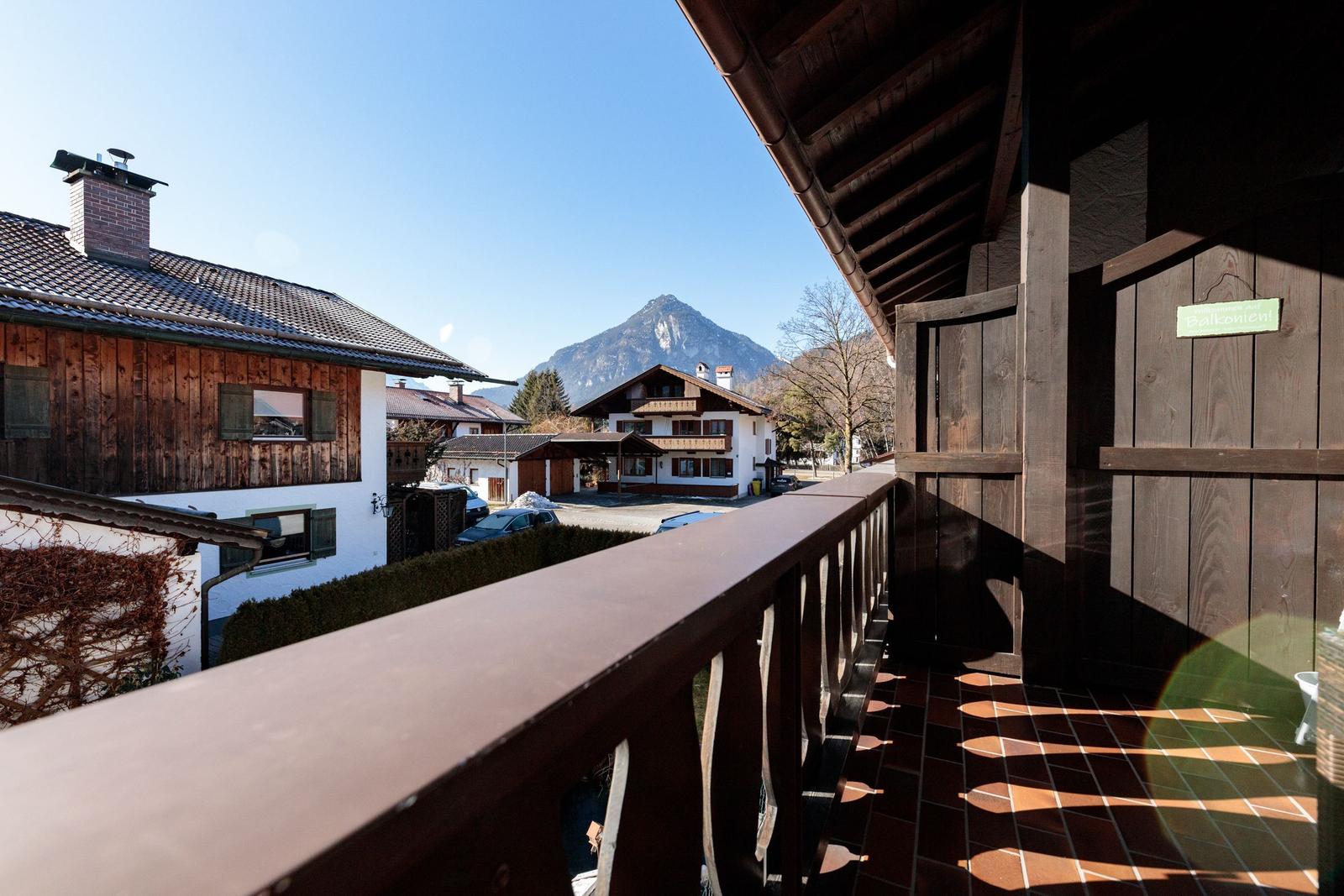 Balkon mit Holzgeländer und Blick auf Berg und Häuser