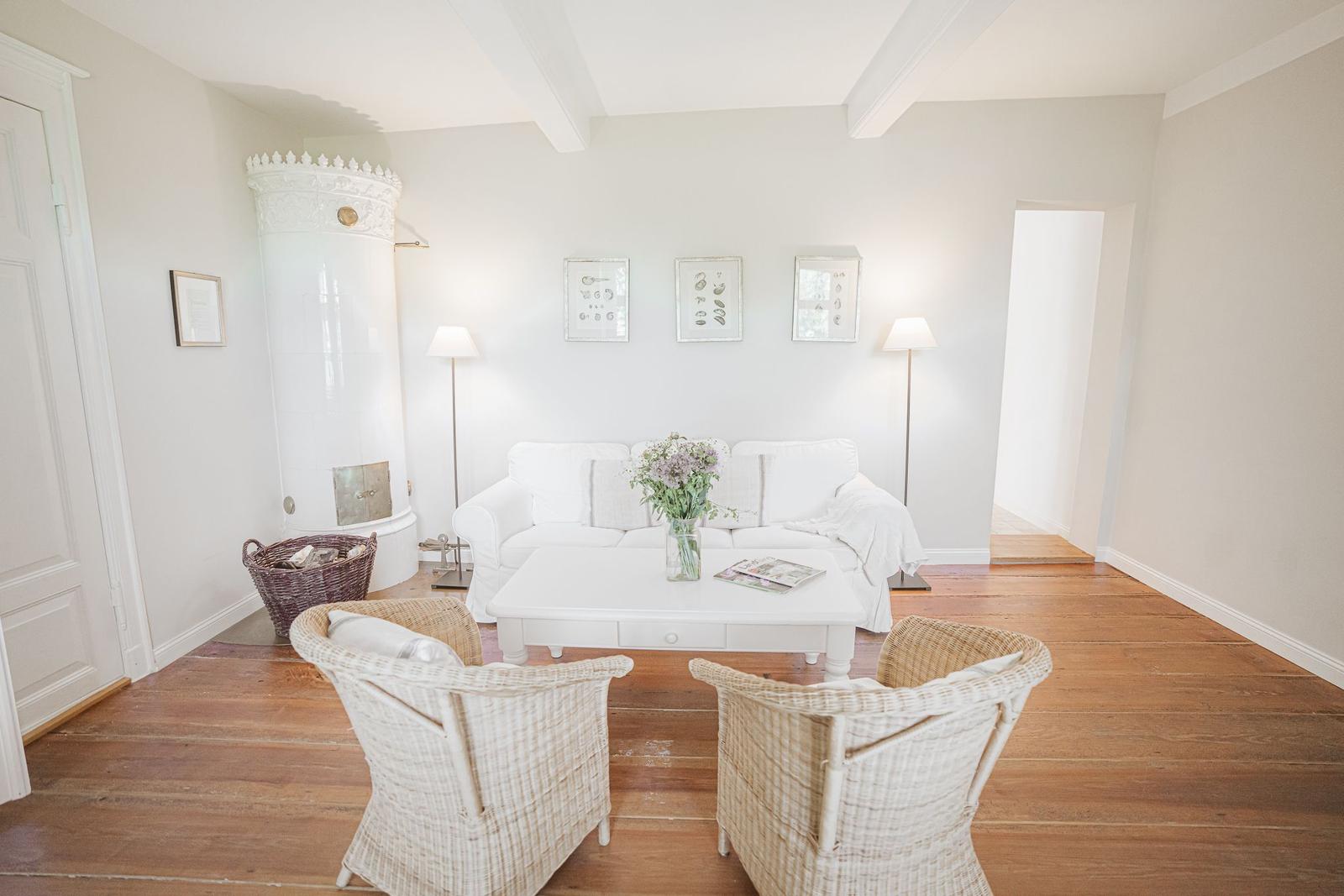 Wohnzimmer mit weißem Sofa, zwei Stühlen und Kamin. Holzboden und Wandbilder.