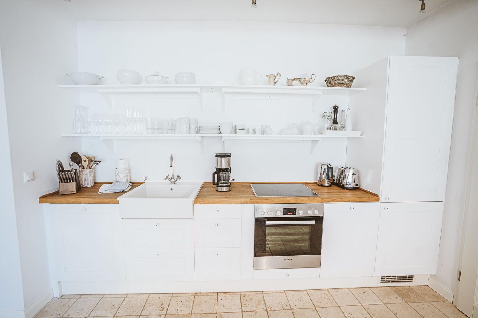 Küche mit weißen Schränken, Holzoberflächen und integriertem Ofen.