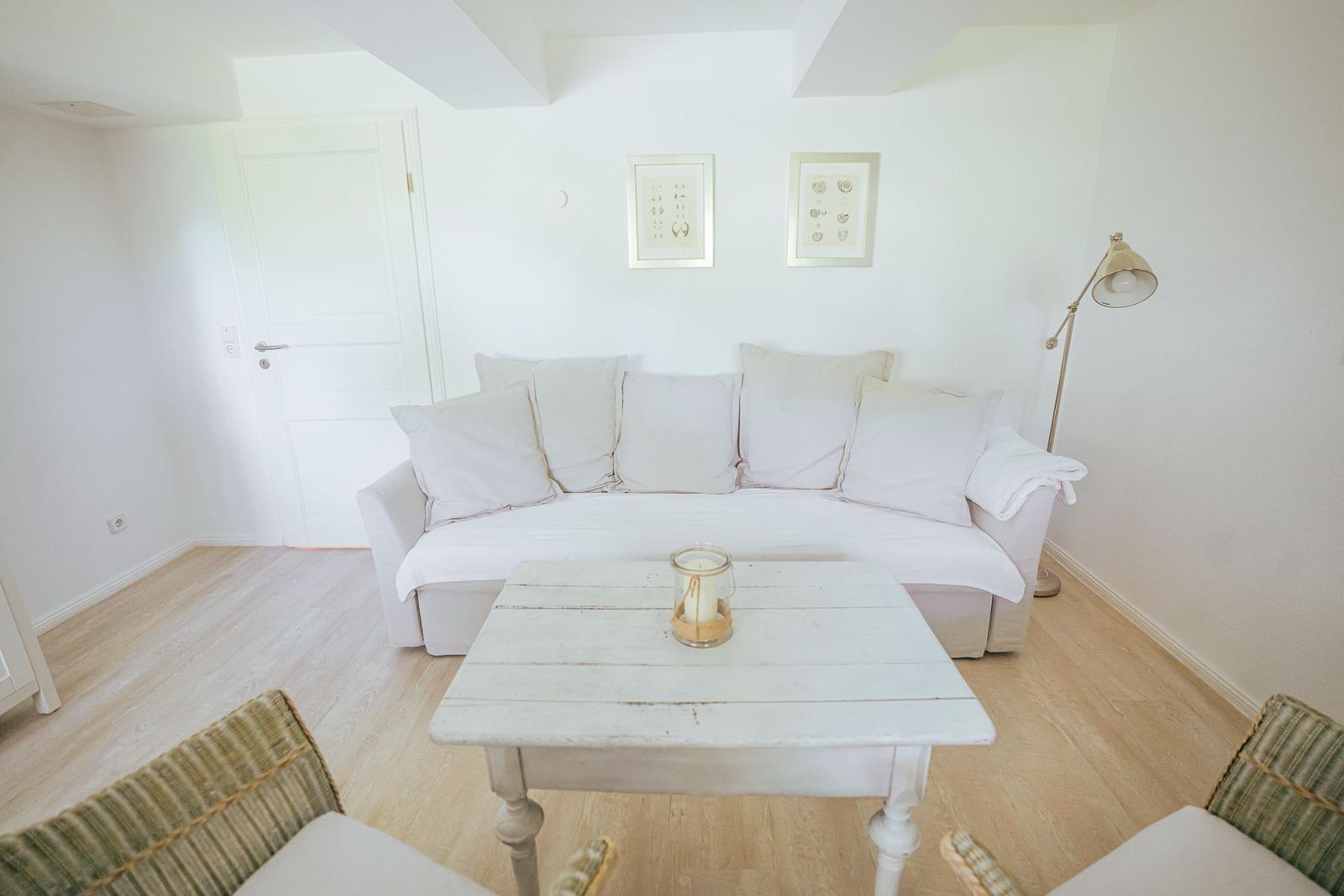 Wohnzimmer mit Sofa, Tisch und Stehlampe.