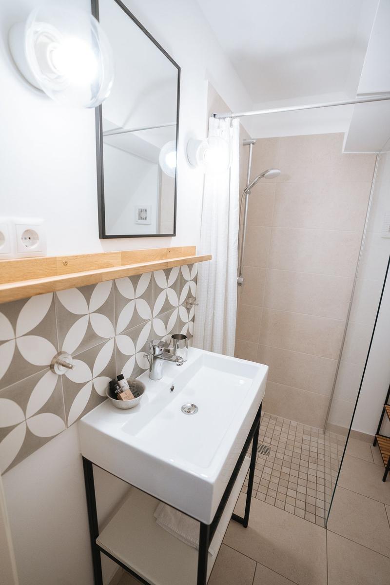 Badezimmer mit Waschbecken, Spiegel und Dusche