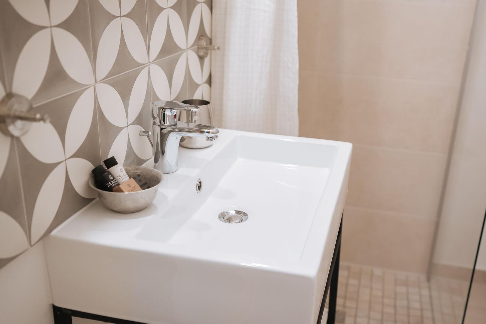 Waschbecken mit modernem Wasserhahn und dekorativen Fliesen im Badezimmer