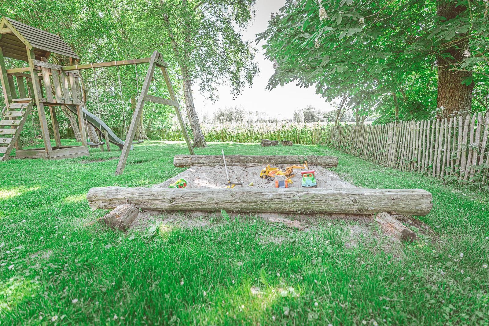 Hinterhof mit Sandkasten, Spielplatz und Grünfläche.