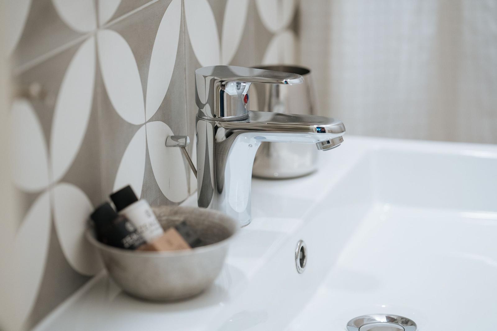 Waschbecken mit Chromhahn und Musterwand