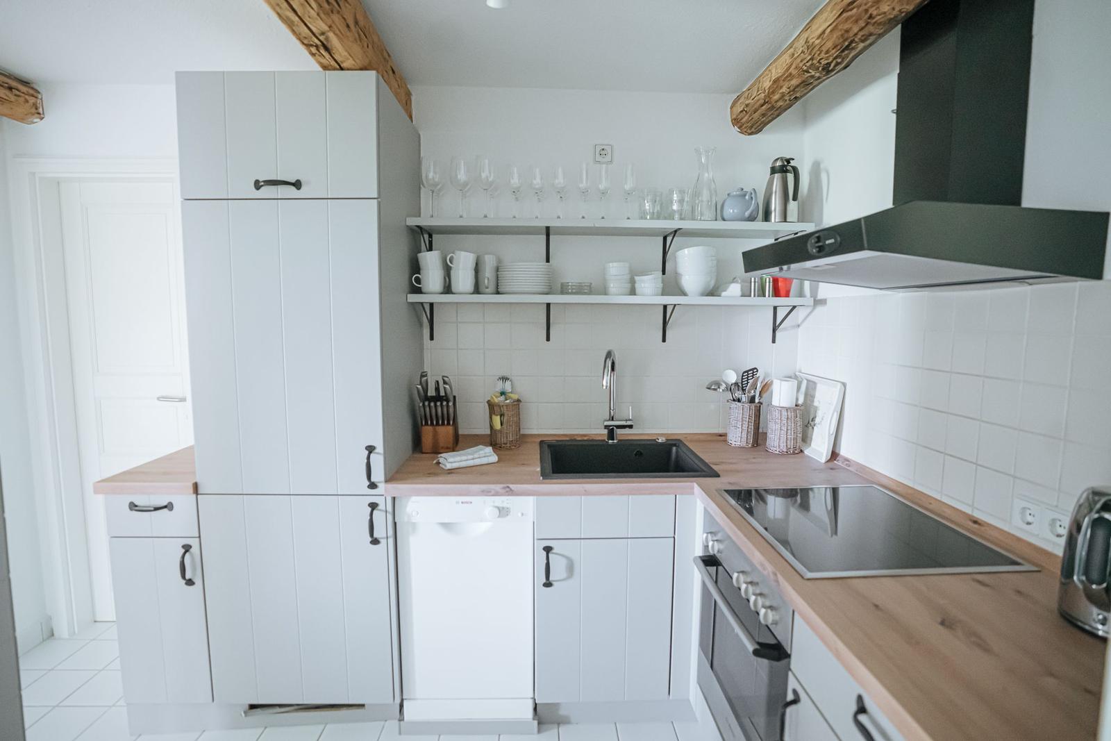 Küche mit Holzoberflächen, weißen Schränken und Edelstahlgeräten.