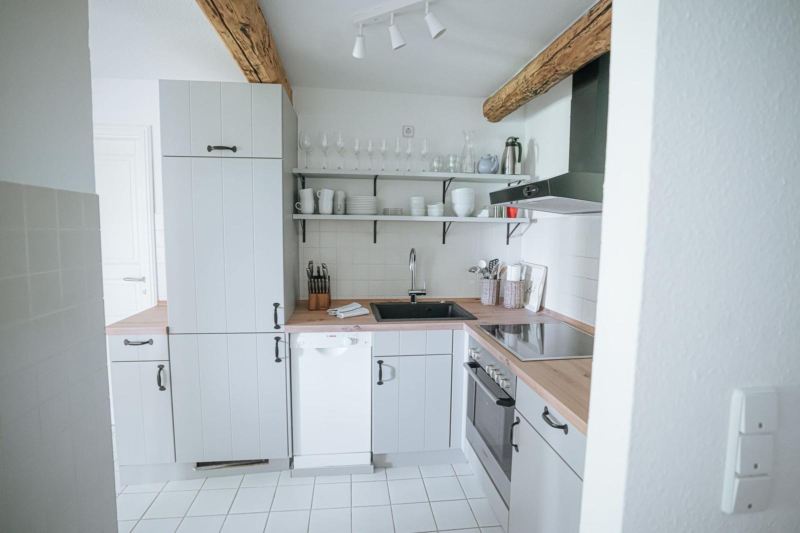 Küche mit hellen Schränken, Holzoberflächen und integriertem Spülmaschinenplatz.