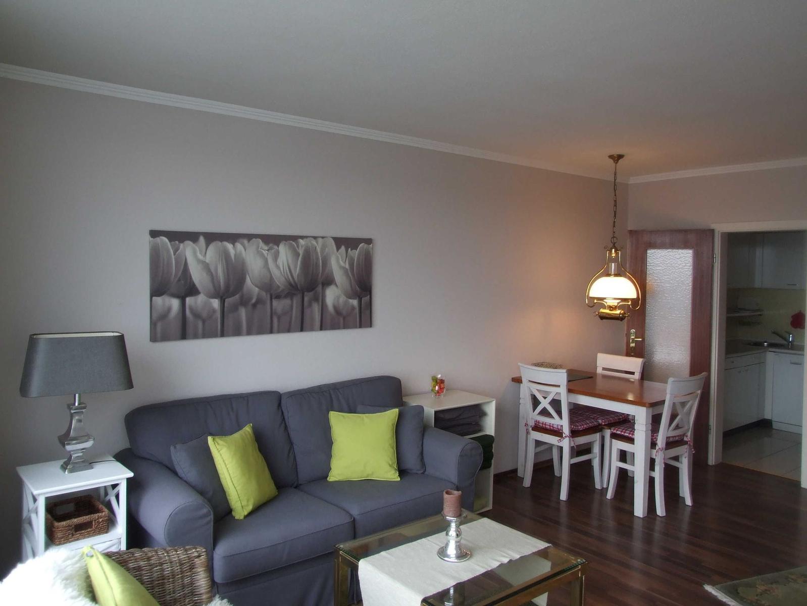 Wohnzimmer mit Sofa, Esstisch und Küchenbereich